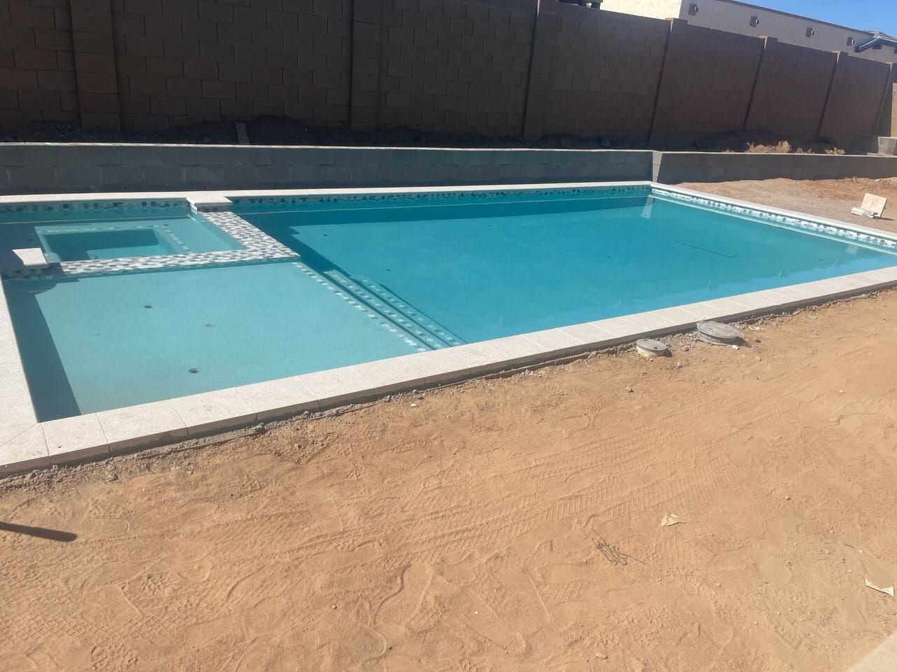 A newly finished pool and spa with mosaic accent tile holding its first fill of water, decking and landscaping still to come.