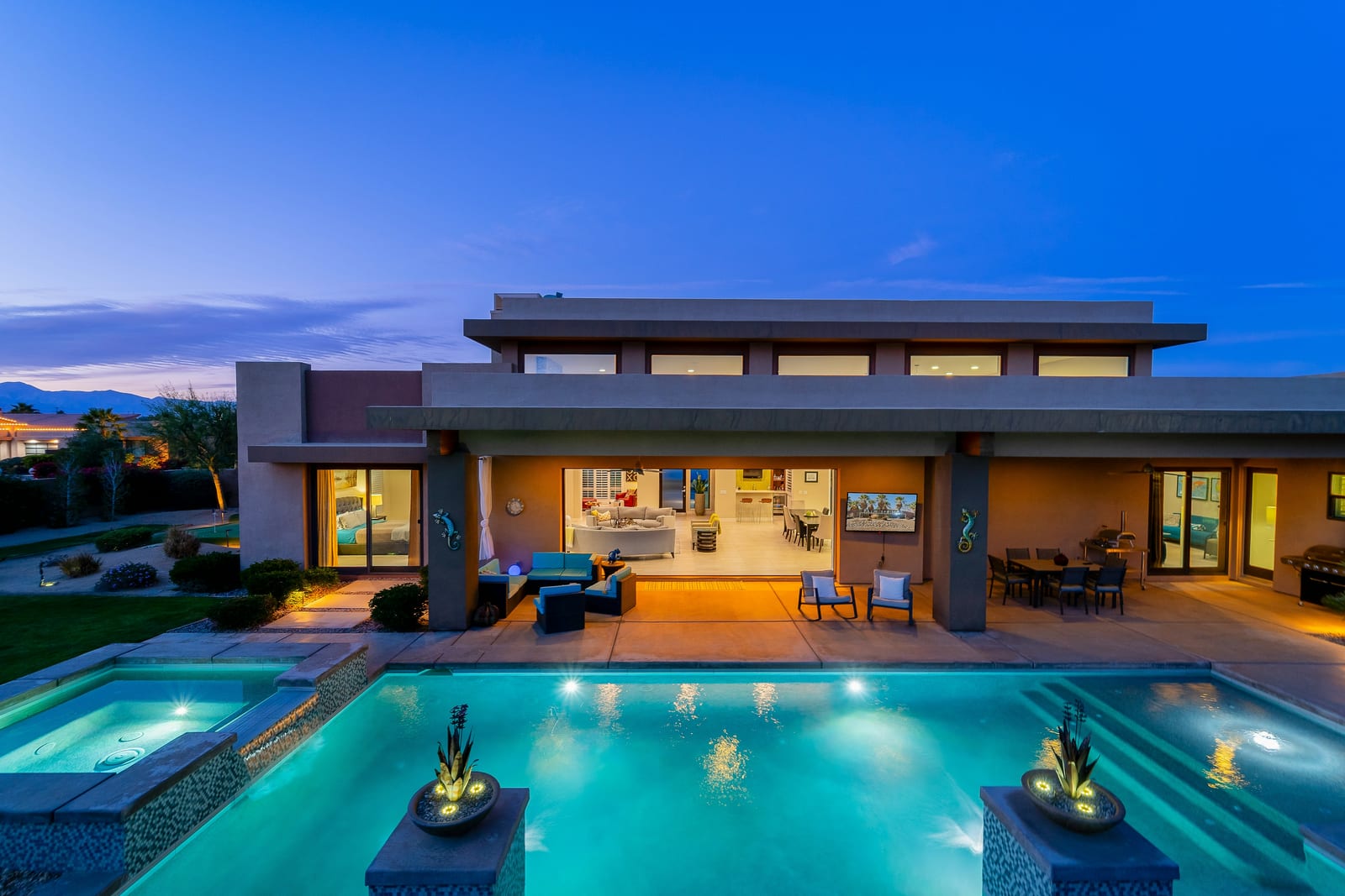 A raised spa spilling into the pool beside it at a desert home.